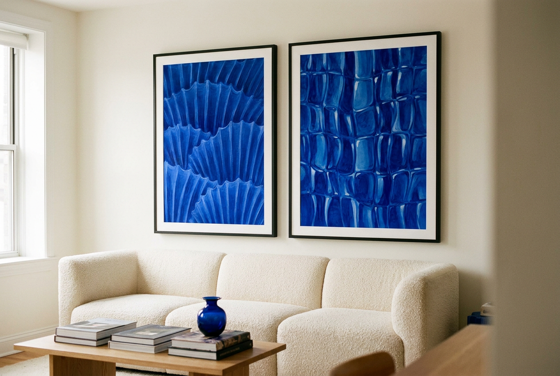 Two oversized cobalt blue abstract prints in black frames above a cream boucle sofa