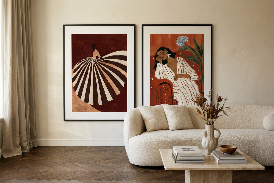 Two oversized burgundy figurative prints in black frames above a cream boucle sofa