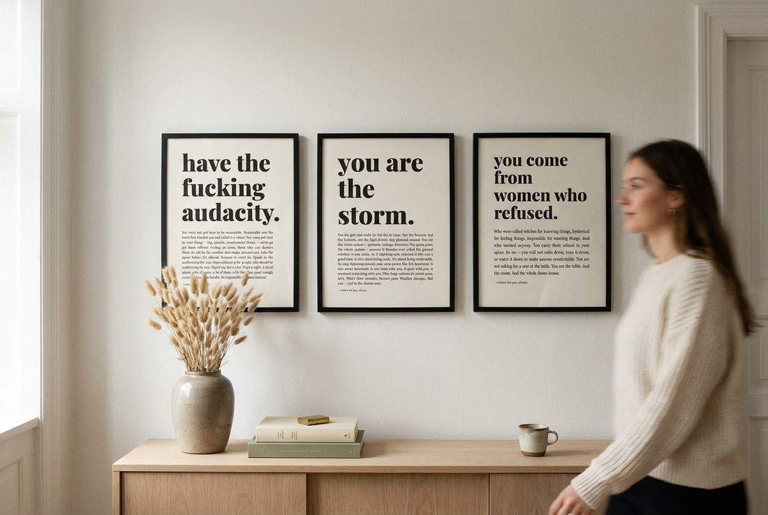 Three white empowerment typography prints in black frames above an oak console
