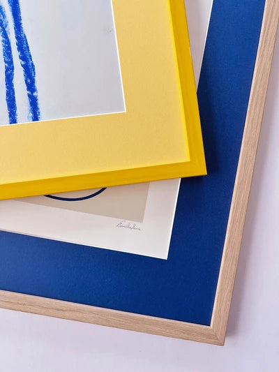 Prints with coloured mats next to an oak frame corner